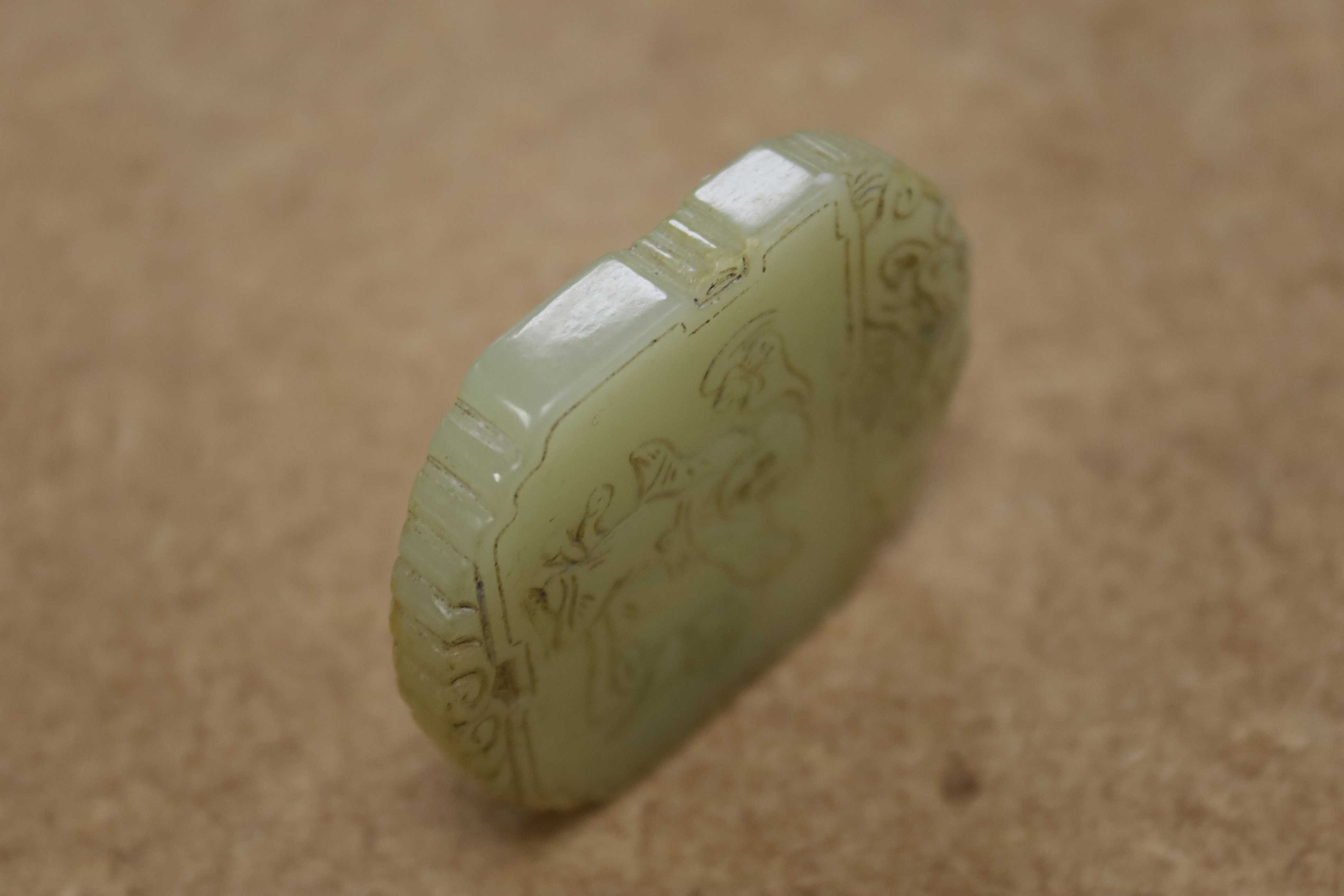 A Chinese pale celadon jade plaque, boy and bats, 5cm wide